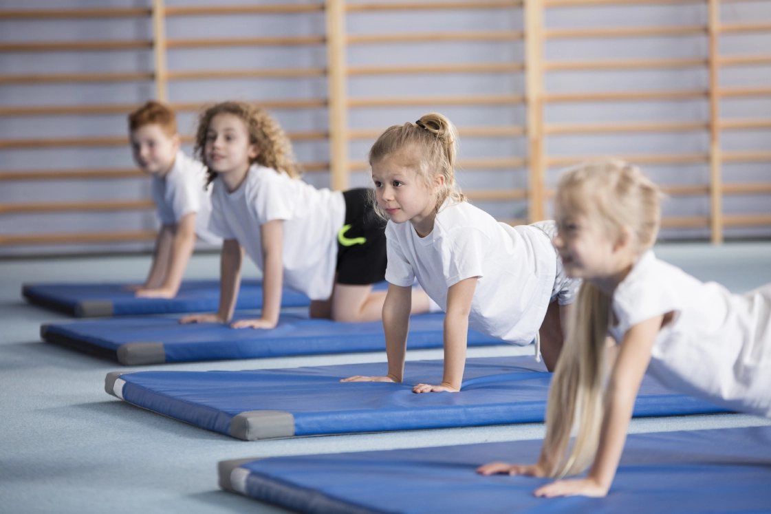 Children practicing yoga poses on mats.