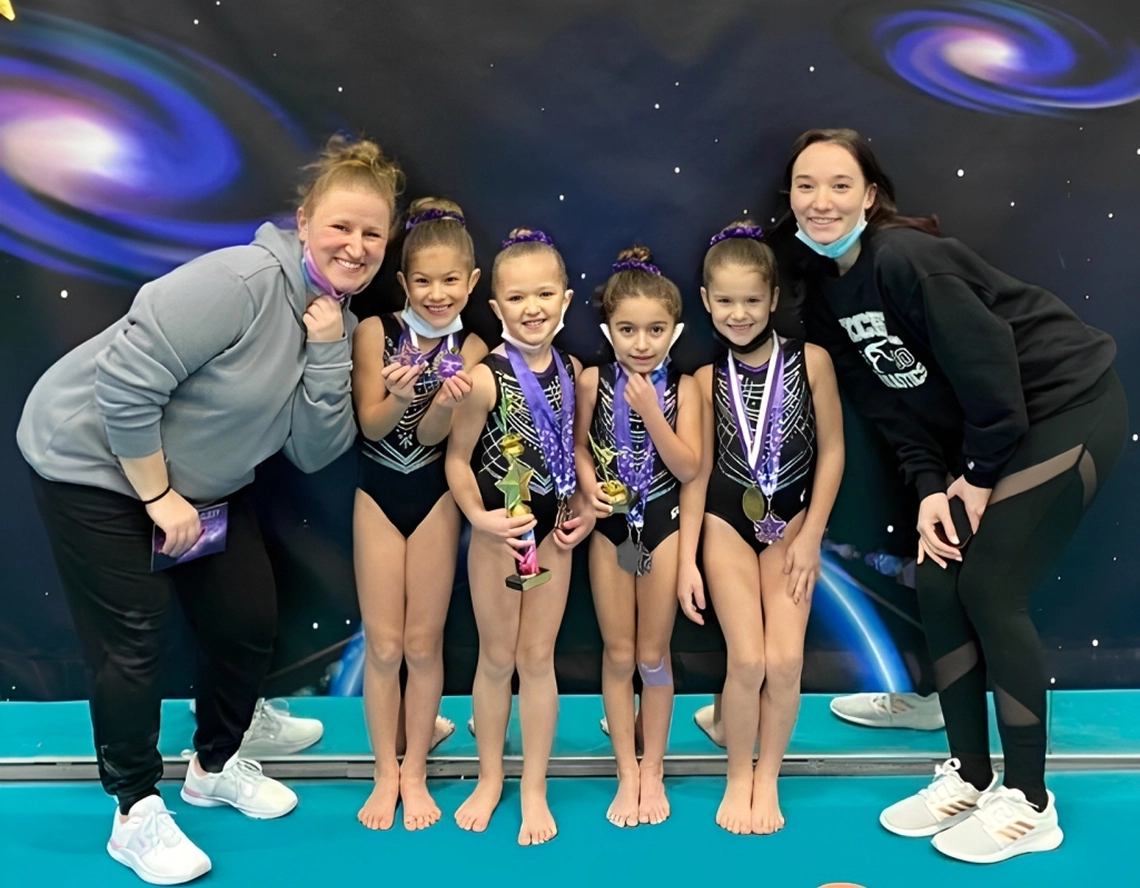 Gymnasts with medals and trophies, smiling coaches.